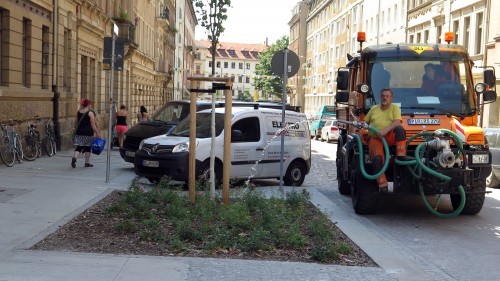 Mitarbeiter des Grünflächenamtes spenden Erfrischung mit dem Schlauch.