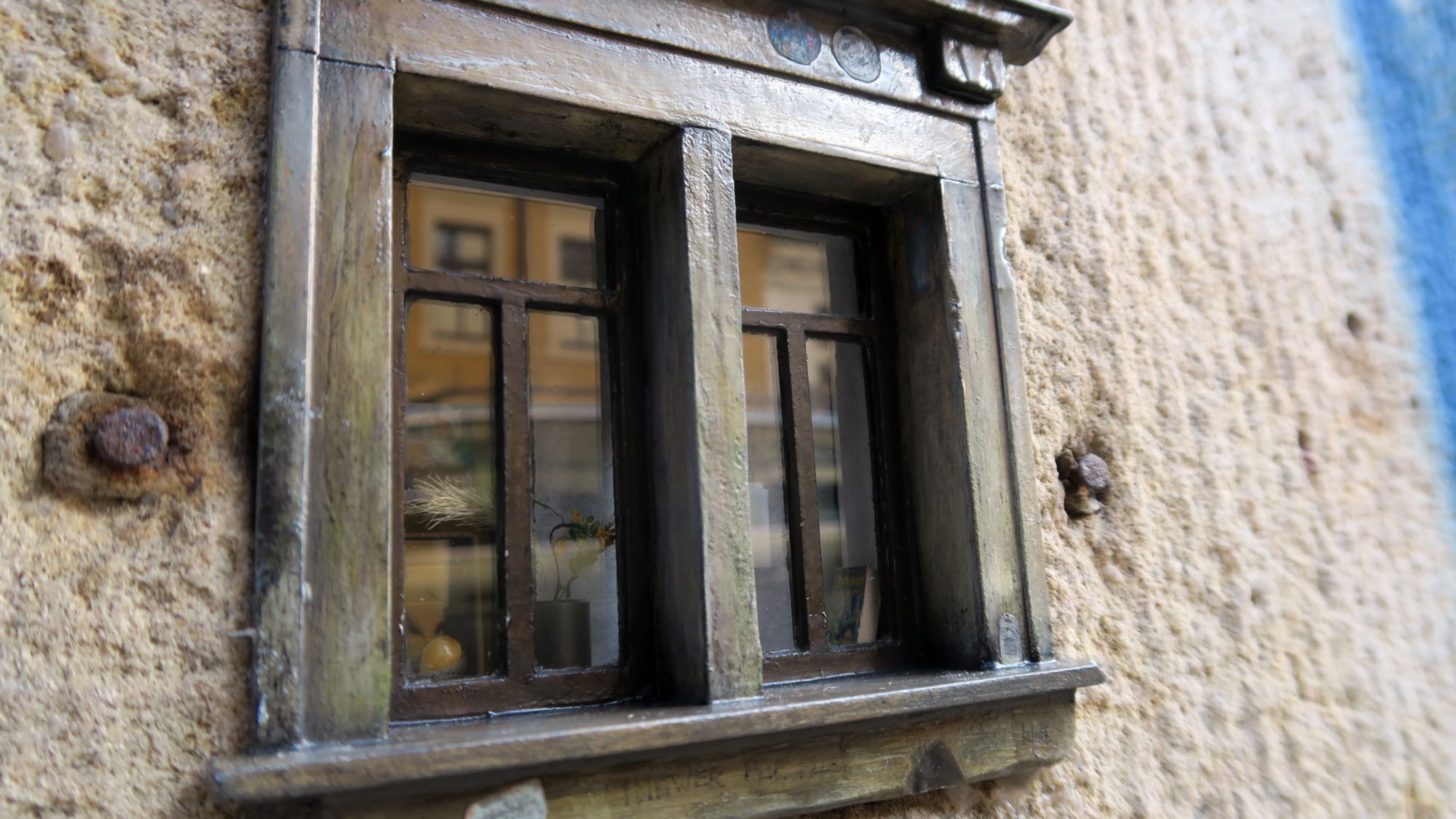 Im Fenster spiegeln sich die Häuser der gegenüberliegenden Straße.