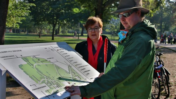 Jan Blüher testet die Infotafel - im Hintergrund: Halina Starkloff vom Grünflächenamt.