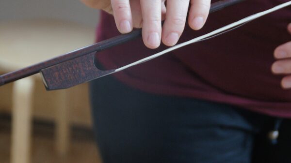 Die Haare dieser alten Violine werden mit einem Stück Holz, dem Steckfrosch, gespannt. Er wird vor dem Spiel eingeklemmt. Foto: Philine