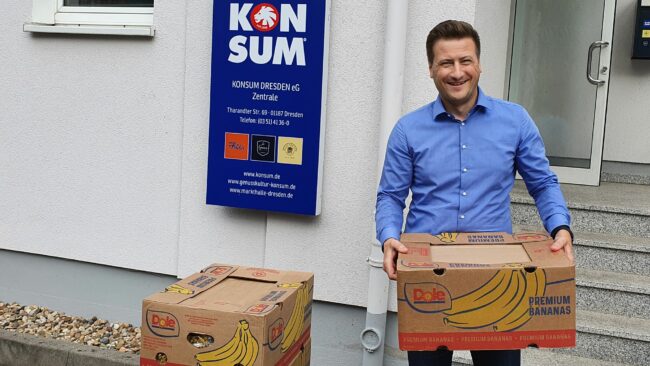 Konsum-Einkaufsleiter Dirk Krompaß mit großen Bananenkisten, die mit haltbaren Lebensmitteln gefüllt sind.