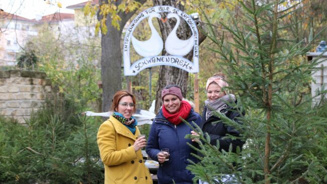 Die Anwohnerinnen Janet, Christine und Antonia proben schon mal den Glühwein. Gemeinsam mit den übrigen Anwohner*innen haben sie den Weihnachtsmarkt vorbereitet.