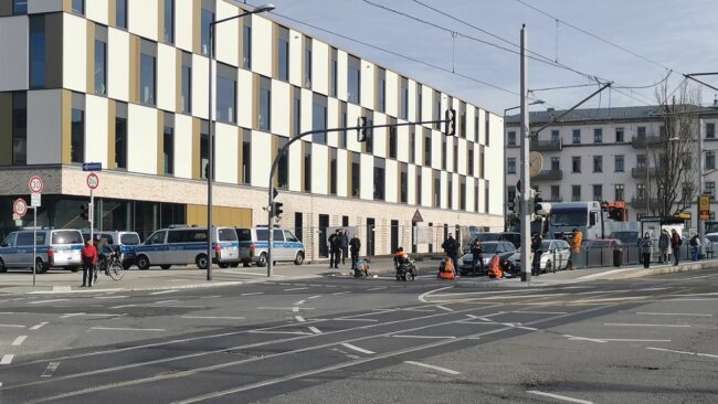 Einige der Blockierenden haben sich offenbar an der Straße festgeklebt, die Polizei ist dabei die Blockade zu lösen.