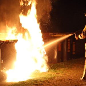 Ein Feuerwehrmann löscht einen brennenden Müllcontainer. Symbolbild - Foto: Roland Halkasch