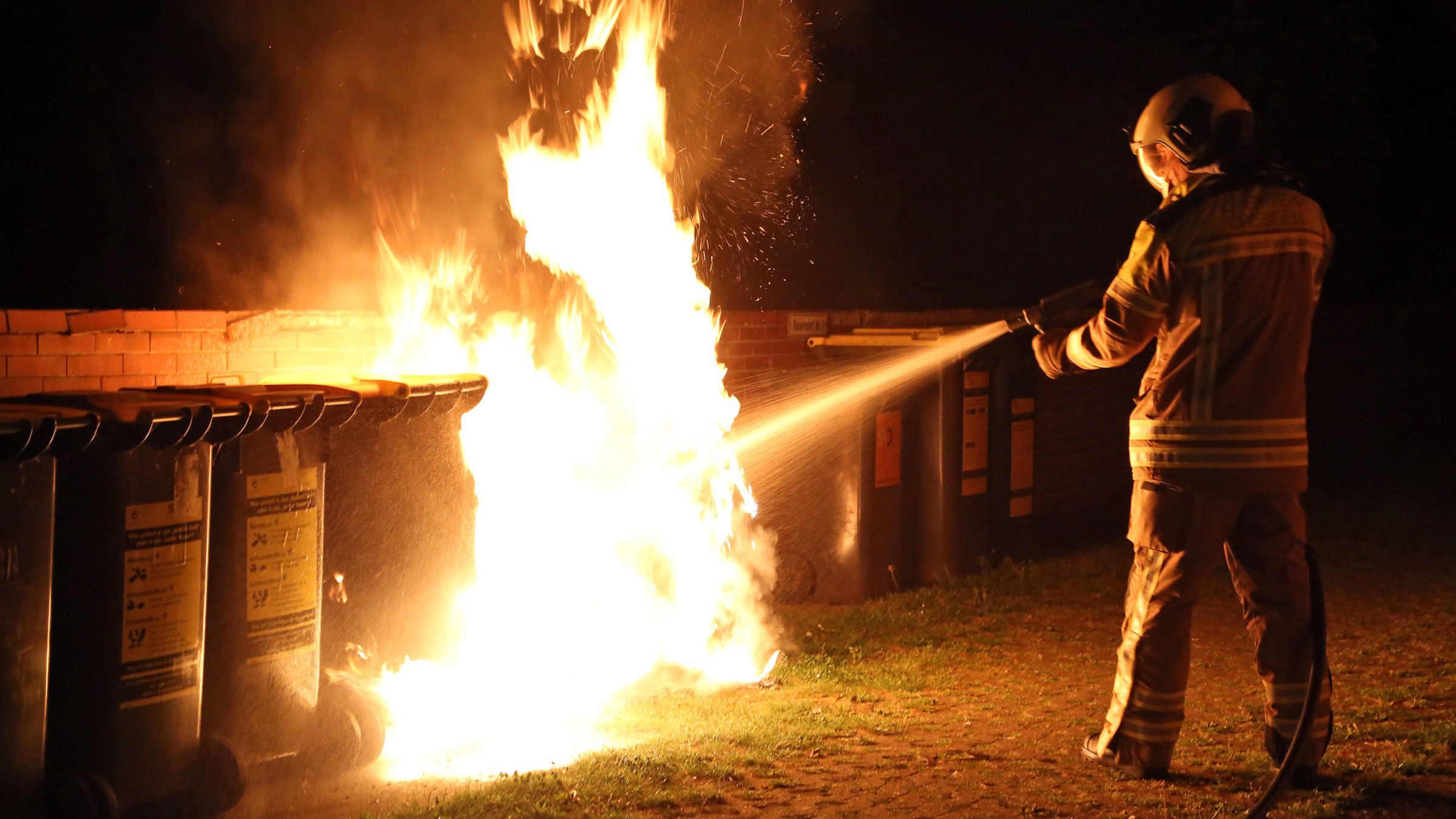 Ein Feuerwehrmann löscht einen brennenden Müllcontainer. Symbolbild - Foto: Roland Halkasch