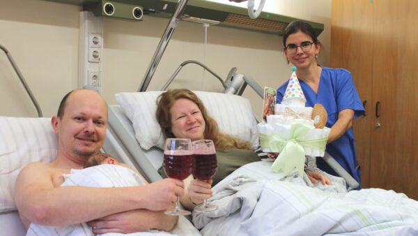 Die Leitende Hebamme Lisa Mühlberg gratuliert den frischgebackenen Eltern mit Brause und einer Windeltorte. Foto: Diako/Victor Franke