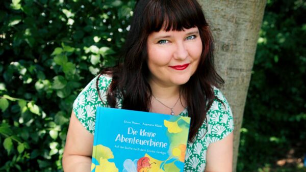 2026-02-25-enna-miau-mit-buch-vor-baum- Foto Ludwig Schmutzler